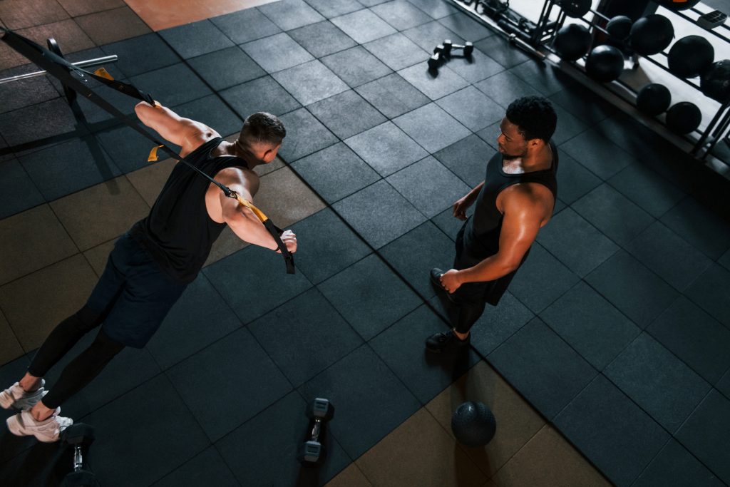 Personal trainer is on job. African american man with white guy have workout day in gym